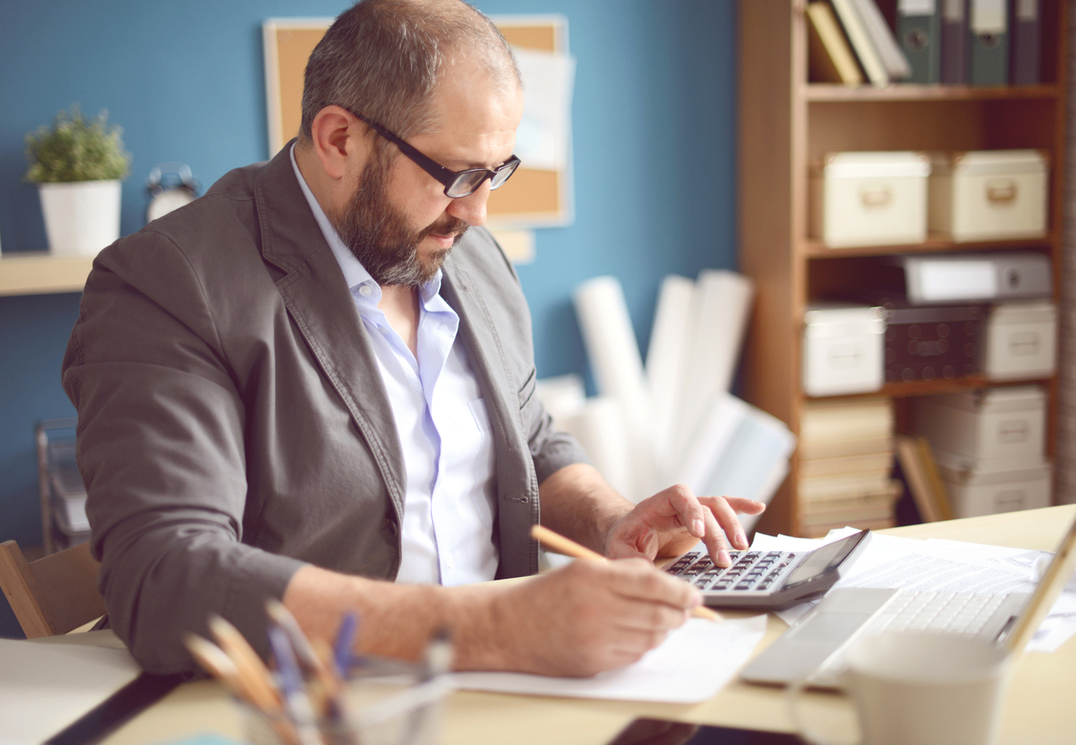 A person sitting at a desk in front of a computer, analyzing financial data.