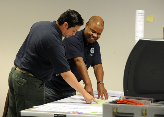 Two people reviewing project plans and maps.