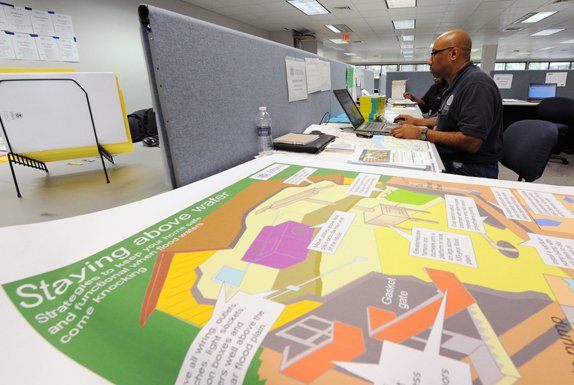 View of FEMA personnel working at a computer over project plans.