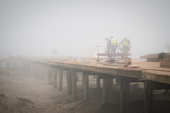 A construction crew works in the fog to repair and rebuild the Avon by the Sea boardwalk after it sustained damage following Hurricane Sandy.