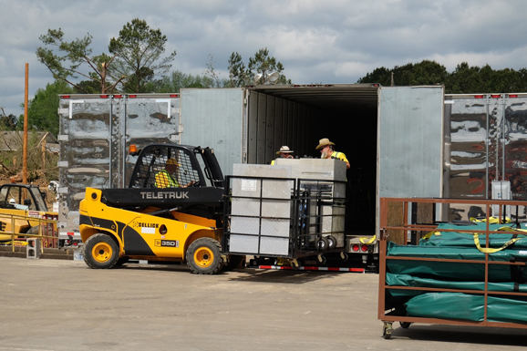 A skid loader offloading a trailer truck.