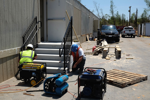 Installers are putting metal hand rails on a set of stairs.