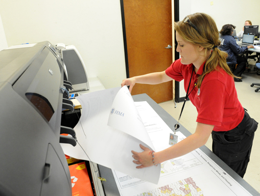 A person printing out large maps and materials from a large-format printer.