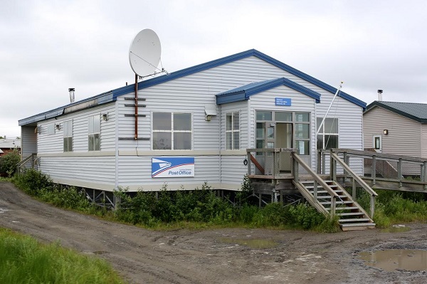 A house elevated on pylons, with plywood storm shutters protecting its windows.