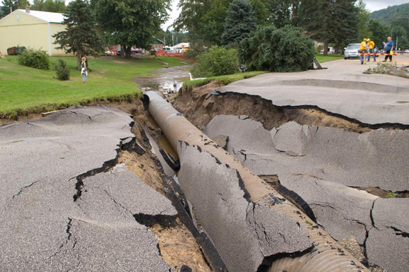 Damage to a road caused by flood water. The road collapsed around a drainage pipe that ran under it.