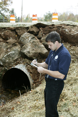 A FEMA Public Assistance Site Inspector reviews repairs made to corrugated pipe drain system damaged during the severe storm and flood in September 2009.