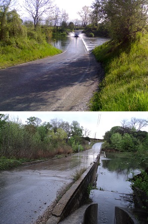 A car driving over a flooded low-water crossing. A low-water bridge crossing a body of water during non-flood conditions.