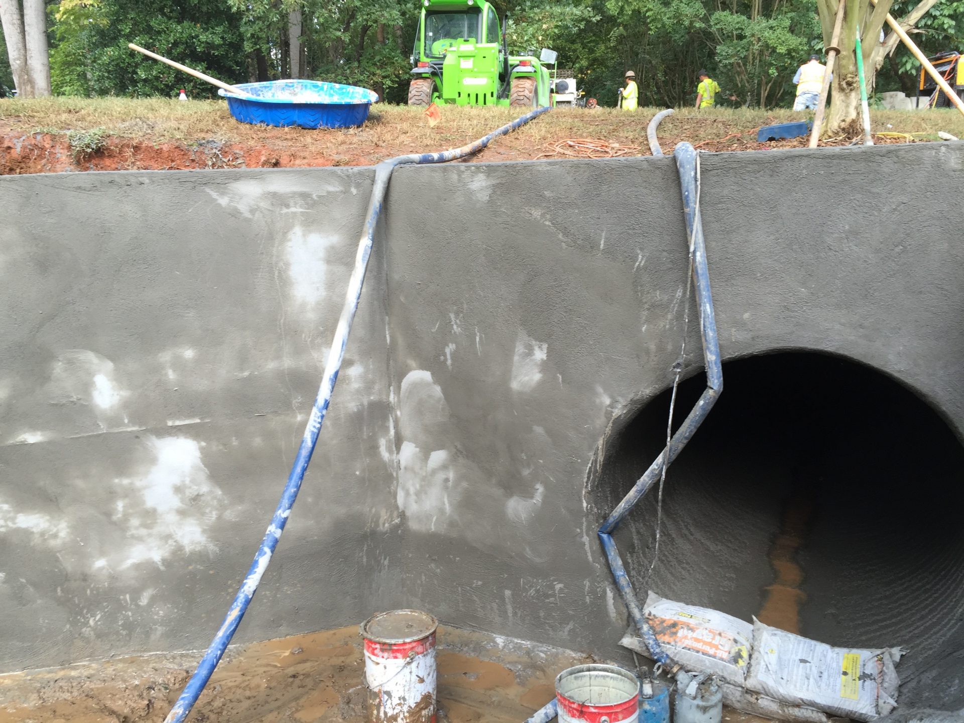 A headwall and wing wall with a tractor and workers in the background.