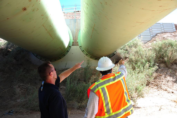 From below, emergency personnel inspect two large pipes that are part of the All American Canal.