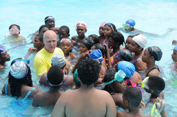 A crowd of people in the water at a community swimming pool.