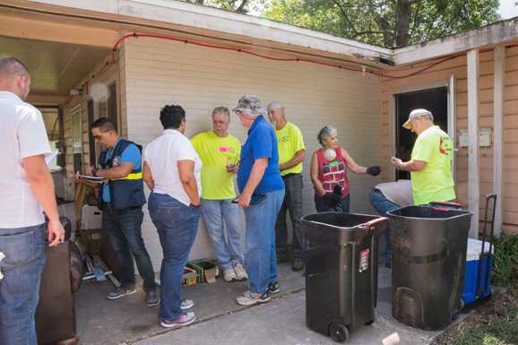 A Preliminary Damage Assessment Team surveys a building damaged by Tropical Storm Harvey while volunteers work on site.