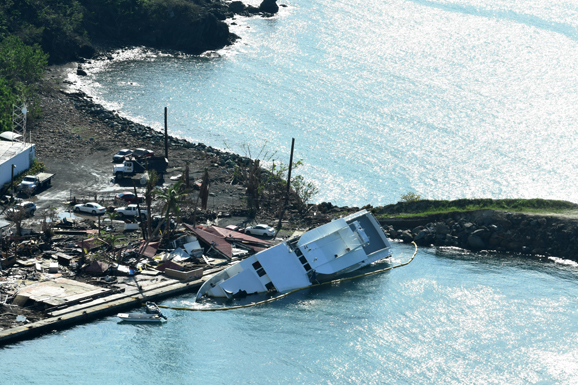 Aerial view of hurricane damage on a shoreline, including a partially submerged boat.