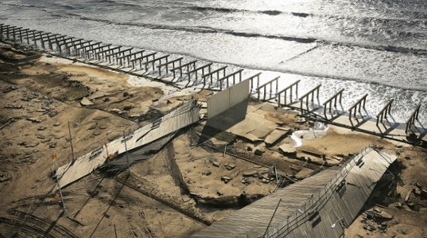 Repairs to the Rockaway Boardwalk in NYC after Hurricane Sandy. A row of pilings line the shore.