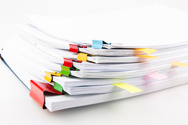 A neat stack of documents held together with colorful clips and marked with tabs.