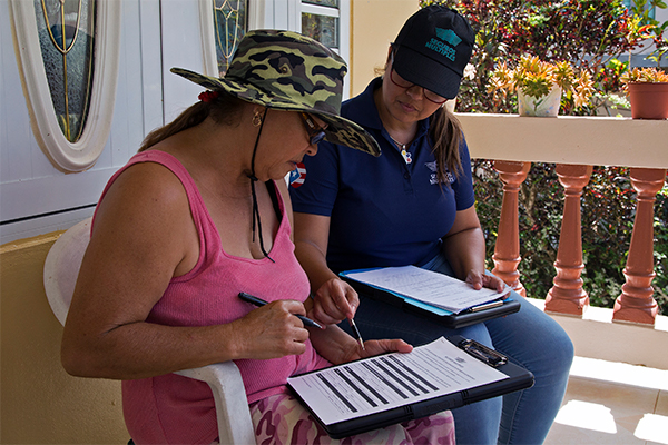 An insurance company inspector is assisting a survivor fill out forms on a clipboard