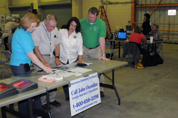 A State Insurance Commissioner providing materials for flood impacted residents at a table