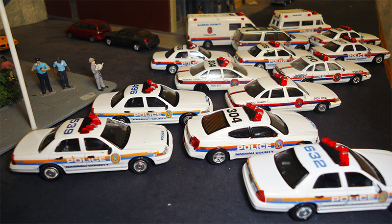 A group of police vehicles. A display of the  Nassau County (New York) Police Department fleet 1/87 Vehicle Club.