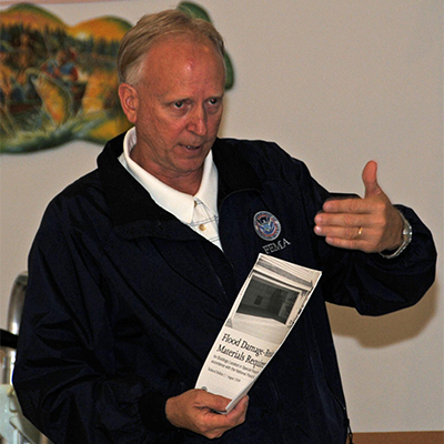 A FEMA flood insurance presenter holding a packet of resources and required materials