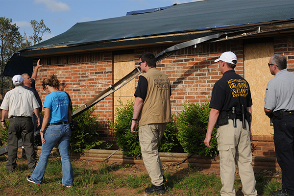 An Oklahoma insurance commissioner and members of the anti-fraud unit reviewing damage to a home