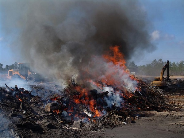 Earthmoving equipment operates at a burning pit near Biloxi, Mississippi.