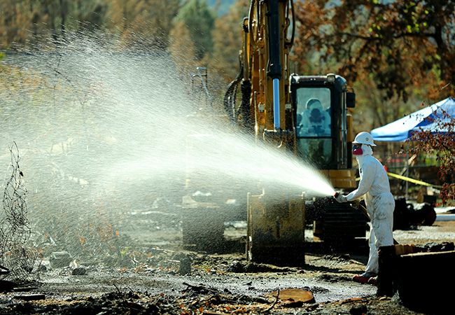 HAZMAT teams spray down homes sites during debris removal