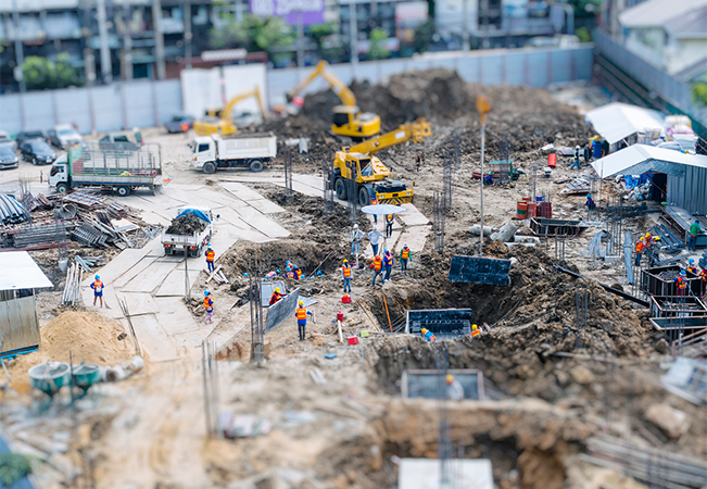 Construction site with trucks and cranes and people working.