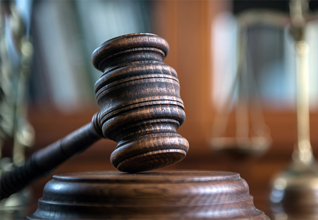 Judge's mallet with scales of justice in the background.