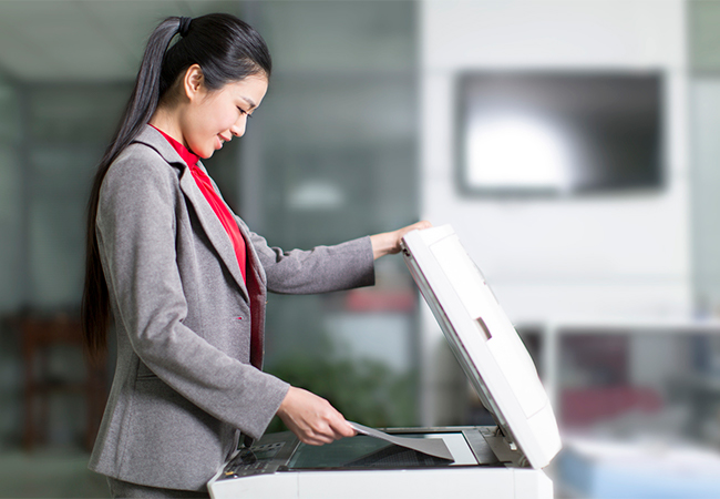 A businesswoman placing documents in a scanner machine.