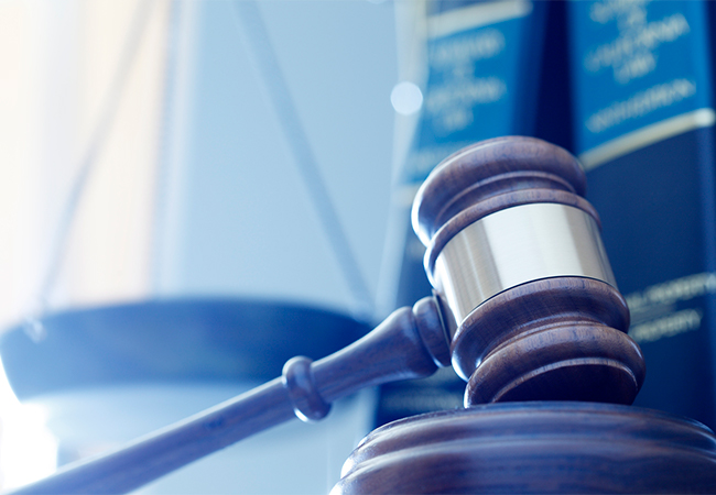 Gavel in front of justice scale and law books.