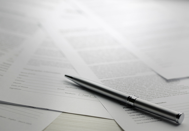 Documents spread out on a table with a pen.