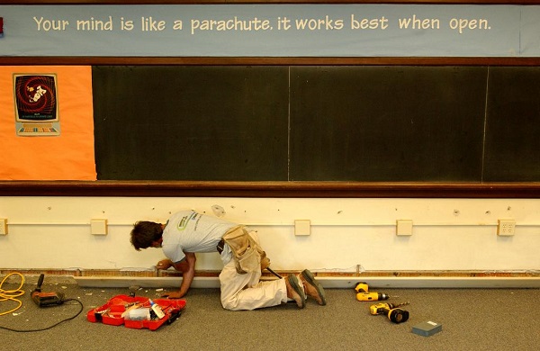 A carpenter makes repairs on a classroom that was flooded at the Central Middle School in downtown Findlay, Ohio. Blackboard banner: Your mind is like a parachute, it works best when open.