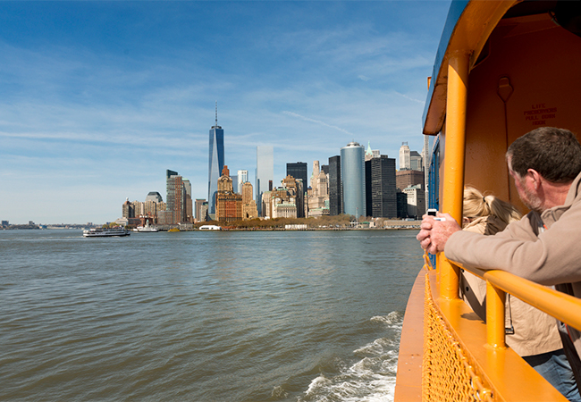 Passengers on board the Staten Island Ferry with the Lower Manhattan skyline behind.