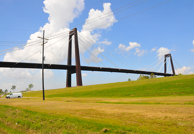 The Hale Boggs Memorial Bridge crossing the Mississippi River in Louisiana with an earthen levee below the bridge.