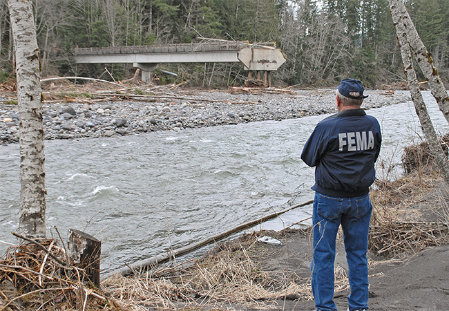 A FEMA Public Assistance inspector looks at the damage to the 180 feet of washed out bridge.