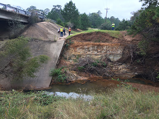 A group of people performing a site inspection of a bridge showing damages from Hurricane Harvey in Texas.