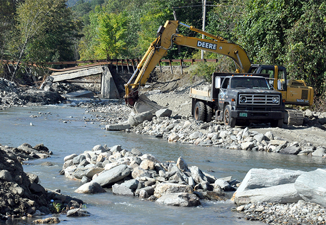 A washed-out bridge in Vermont being repaired by a construction crew.