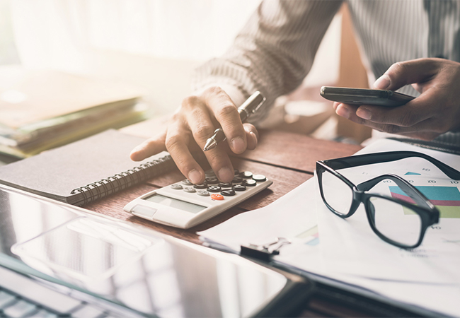 Man working at a desk with financial document and a calculator.