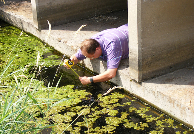 FEMA Technical Assistance Contractor and Bridge Specialist measuring the depth of a scour hole.