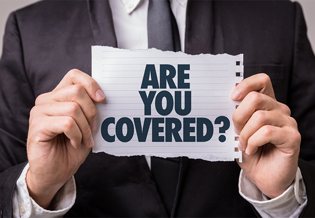 Person in a suit holding a piece of paper that reads, "Are you covered?"