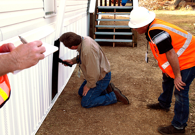 Two people watching a building Inspector at a mobile home