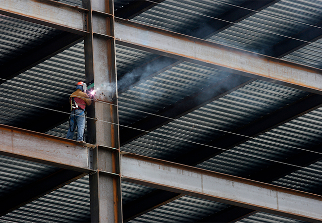 Construction worker welding a beam on a high-rise building