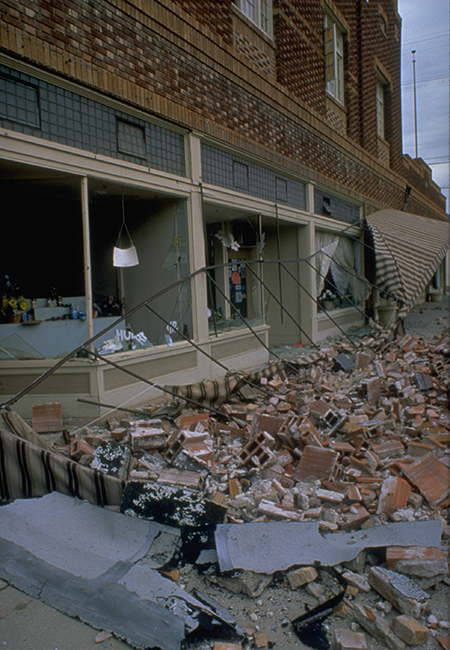A damaged building with contents of the building on the curb.