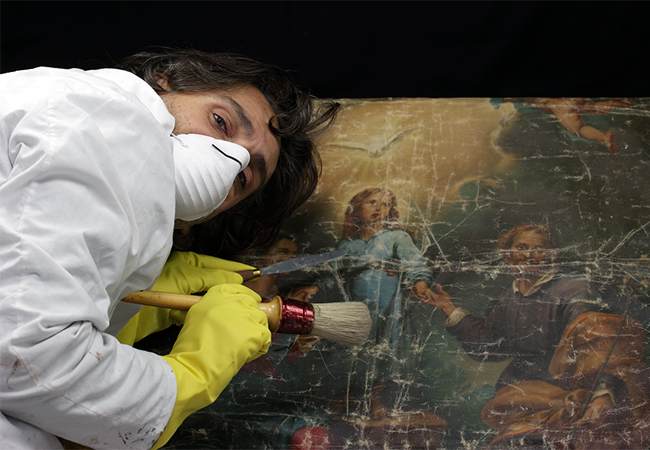 Restorer with a mask and gloves chemically treating an irreplaceable painting