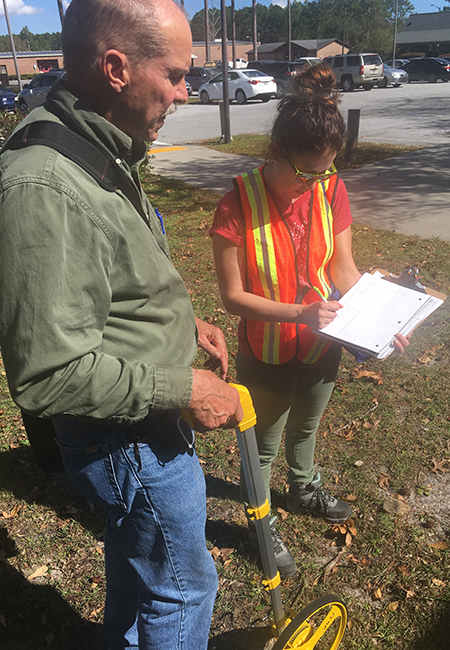 FEMA Public Assistance site inspectors taking measurements outside a damaged facility.