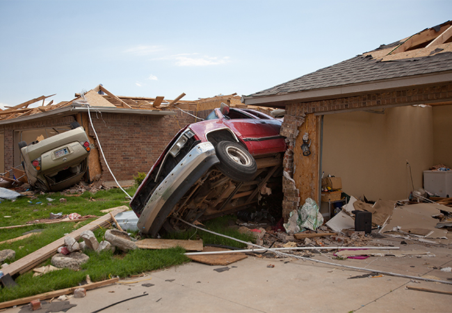 Abandoned vehicles tossed against homes after a tornado