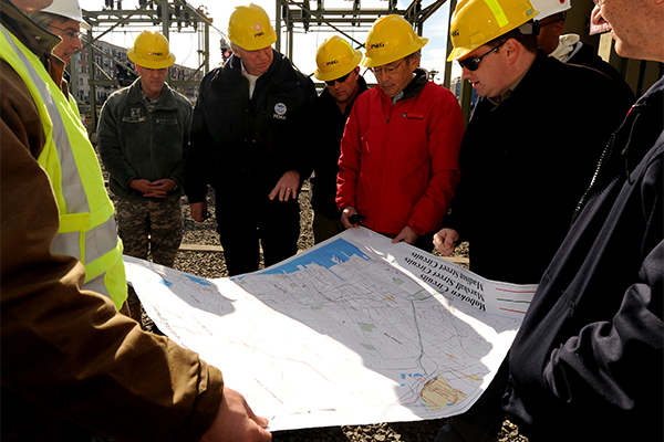 FEMA Deputy Administrator Rich Serino, third from left, discusses power restoration with Department of Energy Secretary Chu, red jacket, along with Public Service Electric and Gas Company engineers at the Hoboken electrical substation.