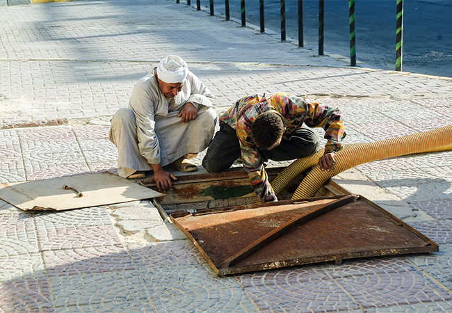 Man pumping sewage from a manhole.