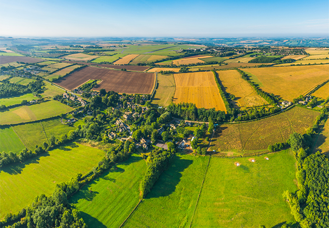 A green pasture of crop fields farms and country villages.