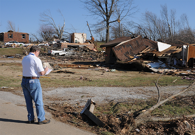 Inspector takes notes in front of a damaged property