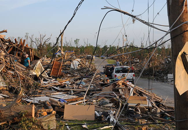 Storm survivor looks for possessions in her destroyed home surrounded by debris.